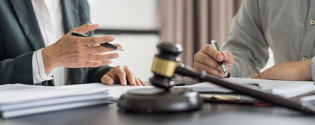Two car accident lawyers are discussing a case at a table with a gavel.