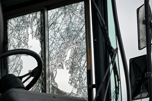 Bus driver's view through shattered glass window of a damaged bus, highlighting the aftermath of a bus accident and the potential for serious injuries and financial repercussions.