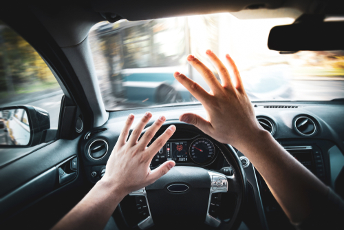 Hands reaching out from a car's steering wheel towards an approaching bus, illustrating a critical moment before a potential bus accident, relevant to legal representation and compensation for victims in Asheville.