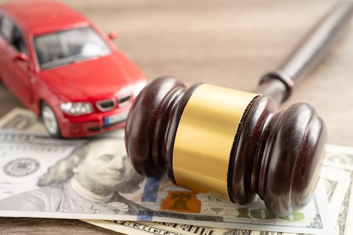 Red car model, gavel on money, symbolizing legal representation and compensation for car accident injuries.