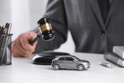 Gavel and miniature car on a lawyer's desk, symbolizing legal representation in car accident cases and the importance of evidence in securing compensation.