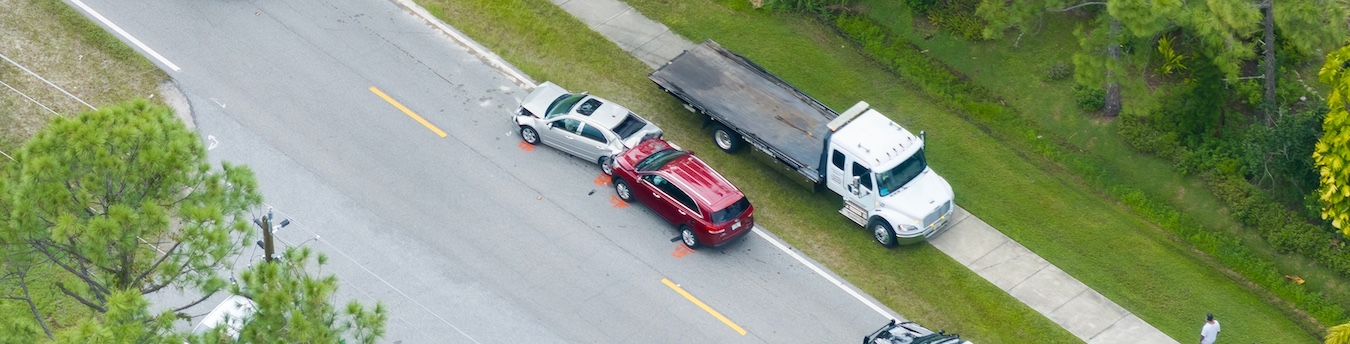 An aerial view of a white sedan, red SUV, and white flatbed truck involved in a multi-vehicle collision on residential street for a car accident claim documentation.
