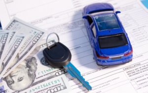 Car accident compensation settlement with cash, keys, and a miniature vehicle representing financial recovery after a collision.