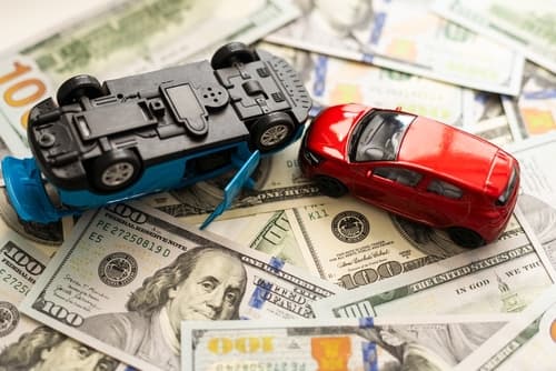 Toy cars on pile of money represent car accident compensation in North Carolina.