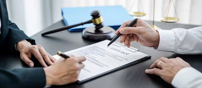 Financial compensation settlement agreement is being reviewed and signed during the injury claim resolution meeting.