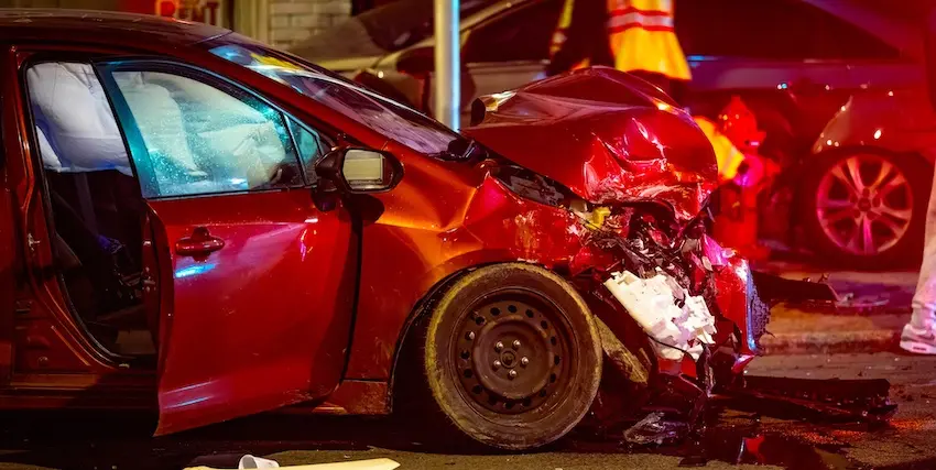 A severely damaged red vehicle at a night accident scene requires an immediate car accident attorney consultation at North Carolina Car Accident Lawyers for claims in North Carolina.