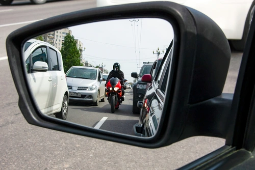 A motorcycle reflected in a car mirror represents bias in motorcycle accident cases.